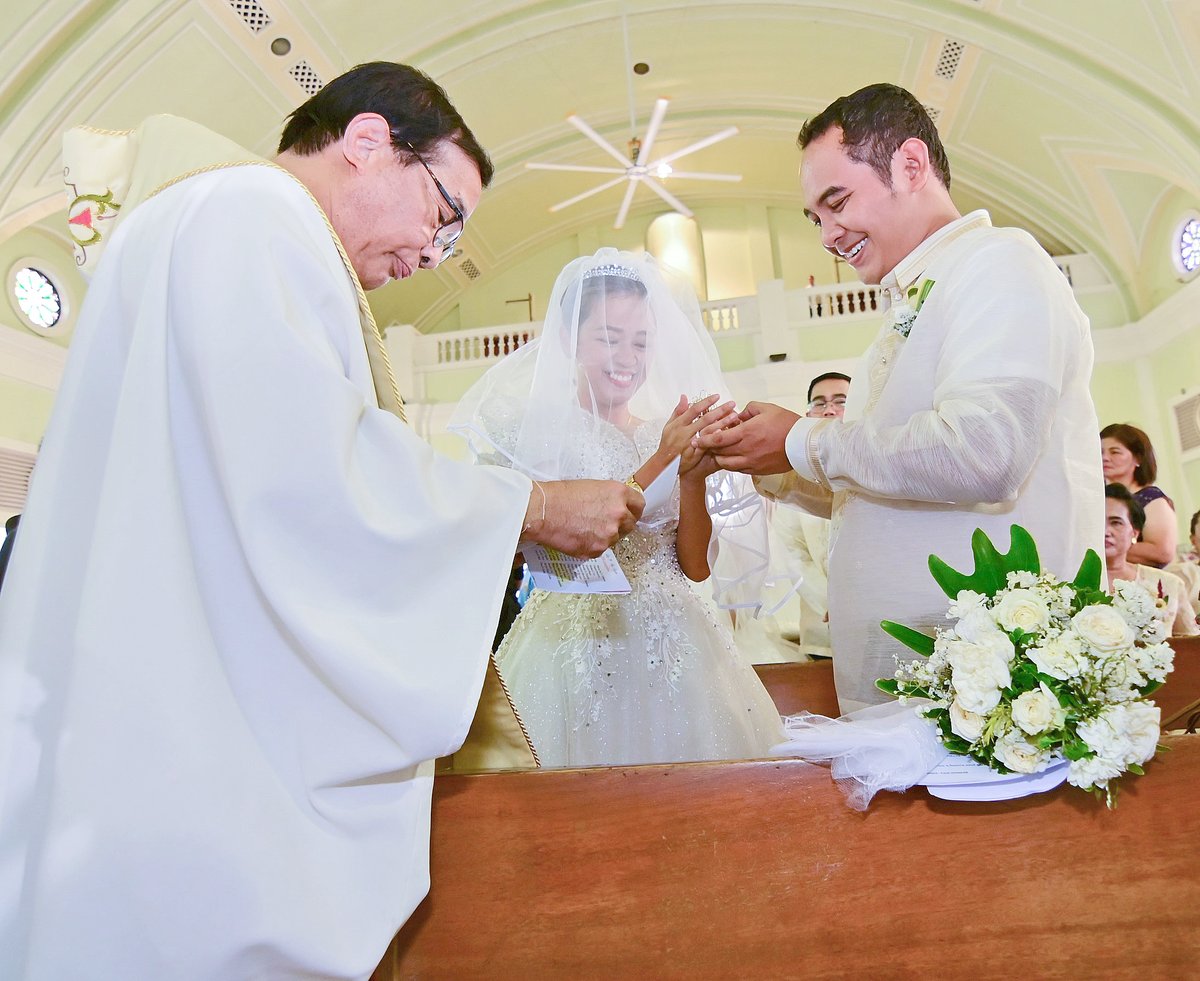 Mary Rellin (center) and Ardyn Lubigan (right) exchange wedding array coins as a symbol of unity.